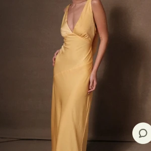 Balklänning  - Säljer en elegant gul långklänning med v-ringad framsida och öppen rygg. Klänningen har en smickrande passform och är perfekt för bal och andra tillfällen. (Har lite defekter längst ner, pga gått på den. Men det är enbart fläckar och inga hål) nypris 1799kr. Obs! Bilderna är lånade av tjejen jag köpte den av, då den är för liten vid bysten!