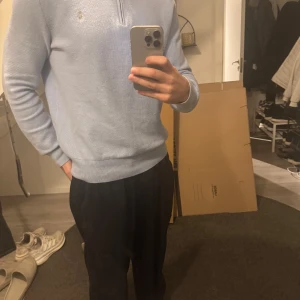 Ljusblå tröja med dragkedja från Ralph Lauren - Säljer en stilren ljusblå tröja från Ralph Lauren med dragkedja vid halsen. Tröjan har långa ärmar och är perfekt för en avslappnad men snygg look. Den är tillverkad i ett mjukt material som känns skönt mot huden.