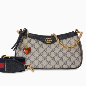 Mönstrad handväska med kedja -  Helt ny och oanvänd. Snygg handväska med ett klassiskt mönster och guldfärgad kedja. Väskan har en dekorativ jordgubbshänge och detaljer i svart. Perfekt för att ge din outfit en lyxig touch. (Kommer med dustbag och låda) pris kan diskuteras.