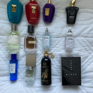 Samling av exklusiva parfymer - En samling av exklusiva parfymer med olika dofter och design. Inkluderar flaskor i olika färger som blå, röd, lila och svart. Märken som Montale, Prada och Maison Margiela finns representerade. Perfekt för den som vill ha en varierad doftgarderob.
