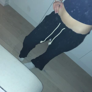 Svarta mjukisbyxor med snörning - Säljer ett par svarta mjukisbyxor med snörning i midjan. Byxorna har en avslappnad passform och är perfekta för en bekväm stil. De är tillverkade i ett mjukt material som gör dem sköna att bära.