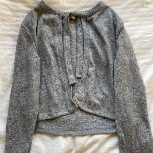 Grå kofta - Säljer en mysig kofta med långa ärmar och knytband. Perfekt för kyliga dagar och ger en stilren look. Passar bra till både jeans och kjol.