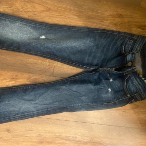Mörkblå jeans från Replay - Snygga mörkblå jeans från Replay med slitna detaljer för en trendig look. De har en klassisk femficksdesign och en bekväm passform. Perfekta för en avslappnad stil.