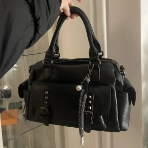 Svart väska - Säljer denna superfina väska som jag har använt en gång. Tillbehöret som hänger på den ingår ej. Säljer då den inte kommer till användning❤️