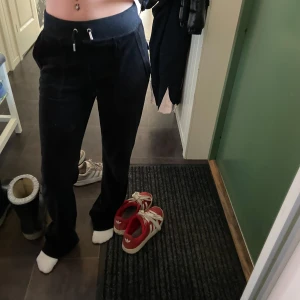 Juicy byxor - Säljer ett par svarta mjukisbyxor med snörning i midjan. Byxorna har en bekväm passform och praktiska fickor med knappar bak. Perfekta för en avslappnad stil.