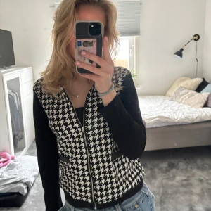 Svartvit rutig kofta med dragkedja - Svartvit rutig kofta/jacka med dragkedja och svarta ärmar. Den har också 2 snygga låtsas fickor på framsidan. Jag skulle säga att den är ganska tunn så funkar bra som kofta/sommar jacka. Står L i plagget men skulle säga att den mer är som en s/m.💕💕