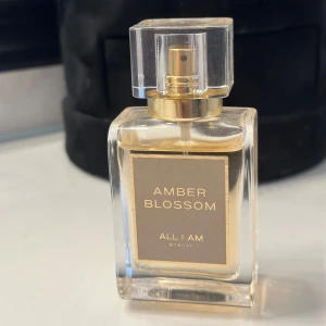 Amber Blossom ALL I AM Beauty  - Amber Blossom är en varm, mjukt blommig och feminin doft. I doften hittar du soldränkt freesia, apelsinblomma och toner av röda bär. Kombinationen av amber, patchouli och musk i basen gör att doften upplevs både modern och klassisk. Amber Blossom är intensiv och mjuk på samma gång och dröjer sig kvar på huden. Toppnot: mandarin, röda vinbär, gröna inslag Hjärtnot: orange blossom, freesia, plommon Basnot: torkad amber, patchouli, musk den är endast använd fåtal gånger 