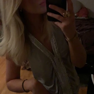 Grå halterneck topp med glittrig detalj - Snygg grå halterneck topp med en glittrig detalj framtill. Perfekt för en kväll ute eller fest. 🪩🪩Fått väldigt mycket komplimanger för denna tidigare och mina kompisar vill alltid låna!! Storleken är M men skulle säga att den sitter mer som en S.