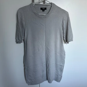 Grå kortärmad tröja från Smog - Säljer en stilren grå kortärmad tröja från Smog i slim fit. Tröjan har en ribbad krage och är perfekt för en avslappnad look. Passar bra till både jeans och chinos.