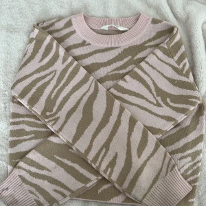 Zebramönstrad stickad tröja H&M rosa/beige - Säljer en stickad tröja från H&M med snyggt zebramönster i ljusrosa och beige. Tröjan har rund hals, ribbade muddar och lång ärm. Perfekt för dig som gillar djurmönster och vill ha en chill look. Storlek 146/152 med skulle säga att det även passar xxs!🥰💗