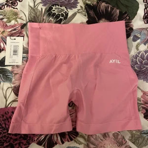 Rosa shorts - Rosa träningsshorts ifrån AYBL, aldrig använda. När jag fick hem dom och testade blev det två små hål samt en liten reva ibak, företaget ville inte ta emot dom och därav säljer jag till någon som är duktig på att sy! Väldigt stretchiga och bekväma.