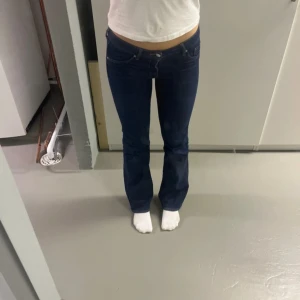 Mörkblå bootcut jeans låg midja - Snygga mörkblå jeans med bootcut passform och låg midja. Klassisk femficksmodell med kontrastsömmar och raka ben som blir lite vidare nedtill. Perfekta för dig som gillar en tidlös och cool stil. Materialet är jeans med lite stretch för extra komfort.