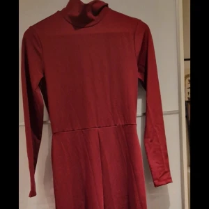 Vinröd jumpsuit med polokrage - Säljer en vinröd jumpsuitmed polokrage och långa ärmar. Jumpsuiten har en enkel, stilren design utan mönster eller detaljer och är tillverkad i ett mjukt, stretchigt material som ger en snygg passform. Perfekt för dig som gillar minimalistisk stil.