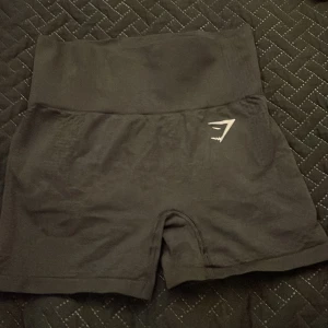 Svarta högmidjade shorts från Gymshark - Snygga svarta shorts från Gymshark med hög midja och kort passform. Diskret Gymshark-logga i vitt på ena benet. Använda max 10 ggr.