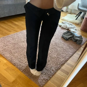 Svarta raka kostymbyxor från Nelly storlek 32 - Snygga svarta kostymbyxor med rak passform och är medel low waist. Byxorna har en stilren look och passar perfekt till en trendig outfit. Materialet känns mjukt och följsamt, och de har diskreta fickor framtill. Perfekt för dig som gillar minimalistisk stil. Dem är några centimeter uppsydda för den var lite långa för mig. Jag är 160 och dem passar perfekt 