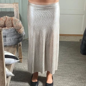 Glittrig guld långkjol från Kappahl✨ - Säljer en glittrig guldrfärgad långkjol från Kappahl i storlek XS. Kjolen har ett skimrande tyg med snyggt strukturerad yta och rak, något utsvängd passform. Perfekt för dig som vill sticka ut med metallic-vibe och cool textur.  ENDAST ANVÄNT FÅTAL GÅNGER