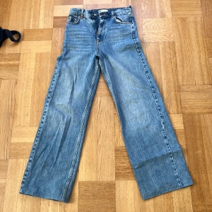 Gina tricot - Klassiska Gina Tricot jeans i ljusblå tvätt med raka, breda ben och fem fickor. Jeansen har hög midja och är tillverkade i robust bomullsdenim. Perfekta för dig som gillar retrostil och vill ha en avslappnad look. De är uppsydda, passar mig på 160 lång!