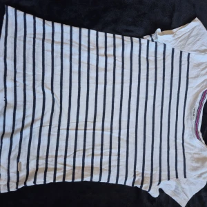 Randig t-shirt  - Vit t-shirt med marinblå ränder och detalj på ena ärmen, aningen urtvättad men fortfarande fin 