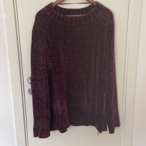 Mörklila stickad tröja med ribbad kant - Säljer en mysig mörklila stickad tröja med bred ribbad kant vid hals, ärmslut och nederkant. Tröjan har långärmade och loose passform, perfekt för att chilla eller hänga med kompisar. Materialet är mjukt och ger en skön känsla mot huden.