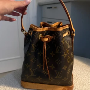 Louis Vuitton monogram handväska - Säljer en klassisk bucket(noe mini) handväska från Louis Vuitton med ikoniskt monogrammönster. Den är i ett bra skick och passar till både vardag och finare tillfällen. Den är perfekt storlek enligt mig, man får plats med precis det man behöver. Den har några fläckar på sig som man kan se på bilderna som blivit av regn. Jag lägger ett pris på 6500, kan diskutera vid snabb affär! Kvitto mm finns vid intresse!