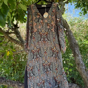 Odd Molly långklänning Evelyn - Supersnygg långklänning från Odd Molly, modell Evelyn Long Dress i färgen Deep Asphalt. Klänningen har ett färgstarkt grafiskt mönster med inslag av orange, beige, blått och rosa, v-ringad hals och långa ärmar. Luftigt material och slits i sidan för extra flow. Storlek 3 som enligt deras storleksguide motsvarar en storlek L. Helt ny med tags/ prislapp fortfarande kvar. 