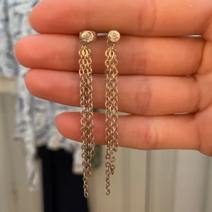 Silvriga örhängen med kedjor - Säljer ett par snygga silvriga örhängen med långa kedjor som hänger ner från en liten glittrande sten. Perfekta för dig som gillar statement-smycken och vill ha något som syns. De är i stainless steel och superbra kvalitet!