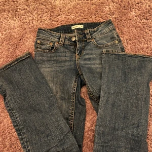 Blå bootcut jeans från Perfect Jeans - Snygga blå bootcut jeans från Perfect Jeans med klassisk femficksdesign och kontrastsömmar. Jeansen har normal passform och är tillverkade i slitstarkt denimtyg. Perfekta för dig som gillar en tidlös look med lite utsvängda ben. Det har lossnat en knap där av priset men jeansen är almänt i väldigt bra skick, low waist