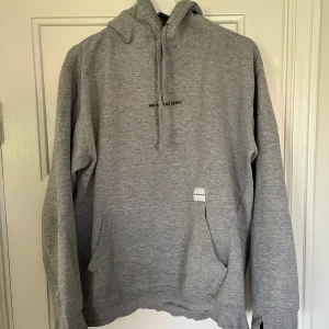 Grå hoodie från MKI Miyuki Zoku - Säljer en stilren grå hoodie från MKI Miyuki Zoku i storlek M. Tröjan har huva med snörning, magficka och diskret logga broderad på bröstet. Tillverkad i mjuk bomullsmix, perfekt för chill dagar. Passformen är normal och ärmarna är långa.