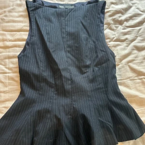 Blå topp med smala ränder från Zara - Snygg blå topp från Zara med smala vita ränder. Toppen är ärmlös och har en figurnära passform. Perfekt för dig som gillar stilrena och trendiga plagg med lite business-vibe.