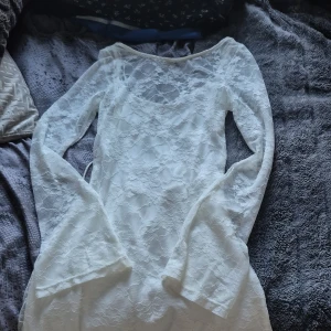 Vit spetsklänning med snörning XS H&m - Supersnygg vit kortklänning i spets med långa ärmar och cool snörning framtill. Klänningen har en figurnära passform och är gjord i ett tunt, spetsigt material som ger en romantisk vibe. Perfekt för dig som gillar detaljer och vill sticka ut med en unik look.