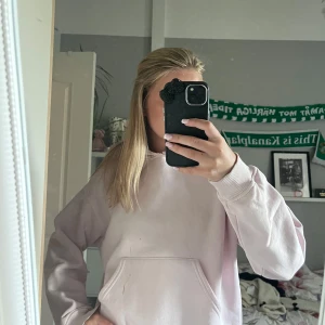 Ljusrosa hoodie med huva - Ljusrosa hoodie med klassisk huva och stor magficka. Perfekt för chill dagar och har långa ärmar med ribbade muddar. Enkel och stilren design utan mönster eller logga. lite trasig och har en fläck men inget som man tänker på❤️ 