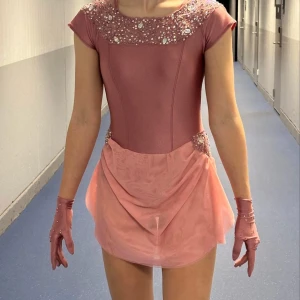 Konståkningsklänning  - Handgjord konståknibgsklänning som bara har används vid en tävling. Mått: Stuss:96cm Midja: 65cm Byst: 84cm Armlängd: 15cm Kjollängd: 46cm, motsvarar xs-s. Den är stretching i materialet så dina mått behöver inte vara identiska för att den ska passa. Handskar samt hår accessoar följer med. Köpt för 3000kr