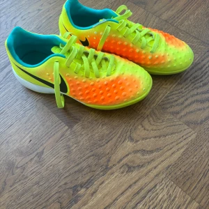 Nike fotbollsskor i neon och orange - Säljer ett par grymma Nike fotbollsskor i neon-gult och orange med coola prickar på ovansidan. Skorna har snörning och en rund tå, samt en vit och neonfärgad sula med Nike-logga. Insidan är turkos för extra färgklick. Perfekt för dig som vill sticka ut på planen! Ingen låda tyvärr
