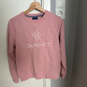 Rosa tröja från GANT - Säljer en rosa sweatshirt från GANT med vit broderad logga på bröstet. Tröjan har rund hals, långa ärmar och är i nytt skick. Tröjan är i storlek 158/164. Tröjan har inga fläckar, lösa trådar eller liknande. Köpt på kidsbrandstore.
