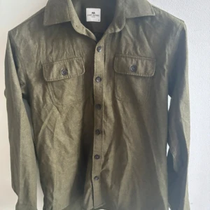 Olivgrön overshirt från John Henric - Snygg olivgrön overshirt från John Henric som passar perfekt nu till sena kvällar när de är lite kyligare. Storlek är M och passar bra allt mellan 179 - 187 cm. Pris kan diskuteras