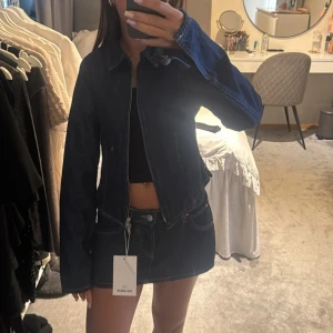 Denim kjol och jacka - Säljer en mörkblå denimkjol och jacka☺️ kjolen är i storlek 32 och har inbyggda shorts och jackan är i storlek xs💞prislappen är kvar på båda