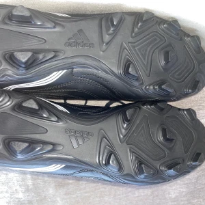 Adidas Copa fotbollsskor svart/vit - Säljer ett par Adidas Copa fotbollsskor i svart med vita ränder. Skorna har snörning och en klassisk design med mönstrad ovandel i skinn och robust dobbsula för gräsplan. Perfekt för dig som vill ha stilrena och funktionella fotbollsskor.