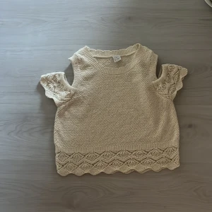Beige stickad topp från Lindex - Superfin beige stickad topp från Lindex med korta ärmar och snygga virkade detaljer på både ärmar och nederkant. Toppen har en rund hals och ett mönstrat avslut som ger extra stilpoäng. Perfekt för dig som gillar en chill och trendig look. Som ny