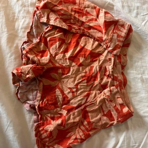 Röda blommiga shorts från Zara - Snygga röda shorts från Zara med beige blommigt mönster. De har en loose passform och elastisk midja för extra komfort. Perfekta för varma sommardagar och har en riktigt chill vibe. Materialet är mjukt och luftigt, troligen bomull eller linne.