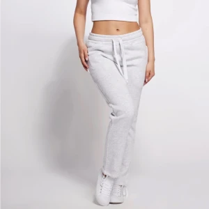 Ljusgrå mjukisbyxor med snörning - Snygga ljusgrå mjukisbyxor med normal passform och raka ben. Byxorna har resår i midjan med snörning, praktiska fickor på sidorna och en bakficka. Perfekta för chill eller träning, tillverkade i mjukt bomullsmaterial för maxad komfort.