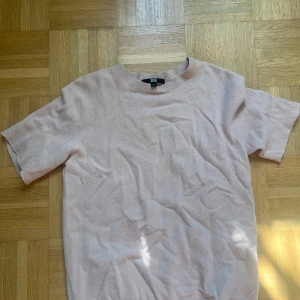 Ljusbeige stickad t-shirt från Uniqlo - En ljusbeige stickad t-shirt från Uniqlo med rund hals och korta ärmar. Tröjan har en mjuk och skön känsla, perfekt för dig som gillar enkel och clean stil. Ribbad kant vid hals och nederdel ger en snygg finish. Passar dig som vill ha en basic topp med lite extra. Dens armar är avklippta och den har ett hål e i den vänstra armhålan men är ingenting som man ser. Skriv vid minsta fundering!💕💕är i kashmir