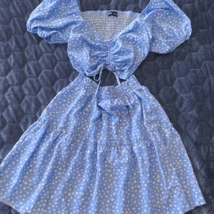 SHEIN tvådelat set blå blommigt topp + kjol strl S/36 - Söt tvådelad outfit från SHEIN i ljusblått med små vita blommor.   Puffärmad topp med knyt + matchande kjol med resår.   Perfekt till sommar, festival eller semester.    Storlek: S/36 Skick: Mycket fint skick.  