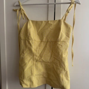Gul rutig linnetopp med knytband - Superfin gul linnetopp med rutigt mönster och smala axelband som knyts upptill. 
