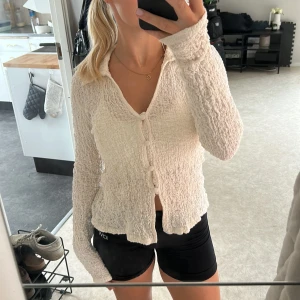 Vit ribbad kofta från Gina Tricot - Säljer en vit kofta från Gina Tricot i storlek S. Den har ett ribbat, krusat material och är långärmad med v-ringning och knappar framtill.💕