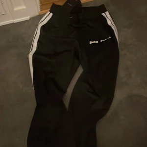 Svarta byxor från Palm Angels - Svarta byxor från Palm Angels, Byxorna har en normal passform och är tillverkade i ett syntetmaterial. Perfekta för en avslappnad stil.