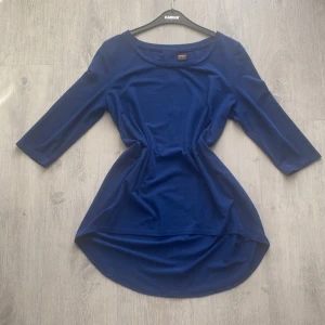 Blå tröja  - Snygg blå topp från Only med trekvartsärmar och rund hals. Toppen har en längre bakdel och knappar i ryggen som ger en extra touch. Perfekt för en stilren look. Sparsamt använd.