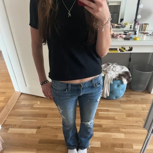 Lågmidjade blå bootcut jeans med slitningar - Snygga blå bootcut jeans med slitningar på låren och knäna från Levi’s.  Jeansen har en låg midja och fransiga benslut för en avslappnad look. Perfekta för en casual stil. Midjemått: 39cm rakt över. Innerbenslängd: 81cm. Står ingen storlek men skulle säga S. Använd gärna köp nu!❤️