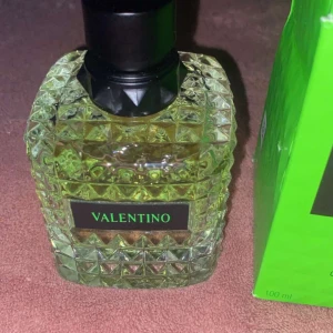 Valentino Donna Born in Roma Green Stravaganza Eau de Parfum - Säljer en lyxig Valentino Donna Born in Roma Green Stravaganza Eau de Parfum. Flaskan har en elegant, kristalliknande design med en grön nyans och svart kork. Förpackningen är i en livfull grön färg med märkets logga i svart. Perfekt för den som vill ha en unik och iögonfallande doft.