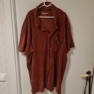 Brun kappa från Kappahl - Säljer en stilren brun kappa från Kappahl. Den har en avslappnad passform med knappar framtill och en klassisk krage. Perfekt för höst och vår.