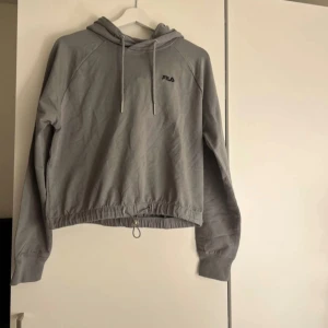 Grå hoodie från Fila - Säljer en stilren grå hoodie från Fila har en huva. Perfekt för en avslappnad look. Passar bra till både jeans och träningsbyxor eller något annat, dessutom är den aldrig använd då jag personligen inte tyckte om den💓Priset kan ockås alltid diskuteras!!